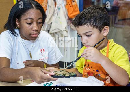 Miami Florida, Kinder-Museum T-Shirt Dekorations-Workshop, Hispanic Junge Kind Kind malen Schwarzes Mädchen weiblich, Teenager Teenager Student volunt Stockfoto