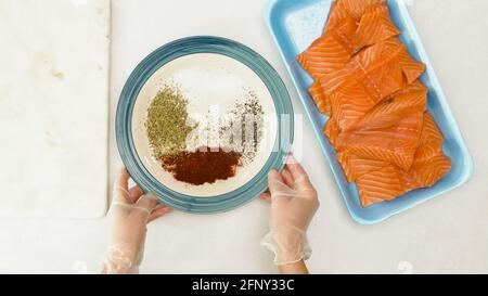 Geräucherter Paprika gerösteter Lachs Rezept. Rohe Fischstücke schließen in Plastikbehälter und Teller mit Gewürzen für Marinade: Mischung aus Paprika, Pfeffer und sa Stockfoto