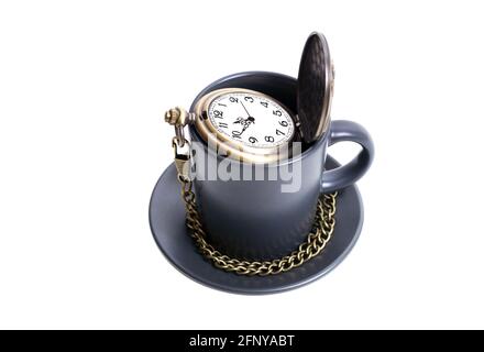 Antike Taschenuhr mit einer Kette in einer Kaffeetasse isoliert auf weiß. Konzept der Kaffeestzeit. Stockfoto