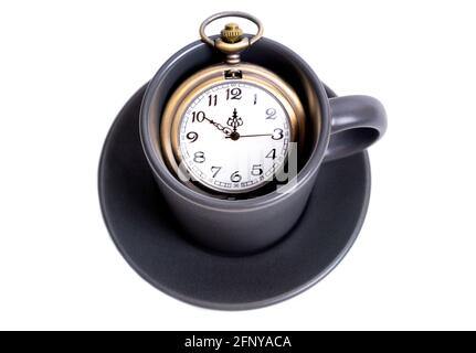 Antike Taschenuhr in einer Kaffeetasse isoliert auf Weiß. Konzept der Kaffeestzeit. Stockfoto