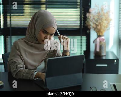 Porträt einer jungen muslimischen Geschäftsfrau, die sich während der Arbeit gestresst fühlt Büroraum Stockfoto