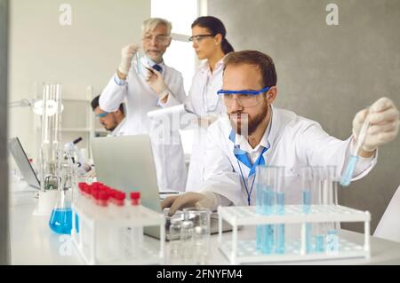 Fokussierter männlicher Wissenschaftler in Schutzbrillen, der medizinische Forschung in macht Labor Stockfoto