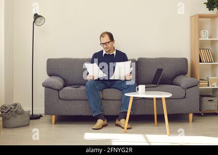 Senioren sitzen auf der Couch zu Hause beschäftigt mit Haushalt Oder Rentenpapiere Stockfoto