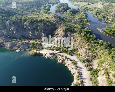 Felsige Ufer des Radon Lake an einem sonnigen Sommermorgen. Luftaufnahme eines alten überfluteten Granitsteinbruchs. Ein malerischer Teich. Stockfoto