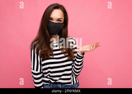 Foto von jungen attraktiven Frau trägt handgemachte Baumwolle Stoff Gesichtsmaske isoliert über bunten Hintergrund Wand. Schutz gegen COVID-19 Stockfoto