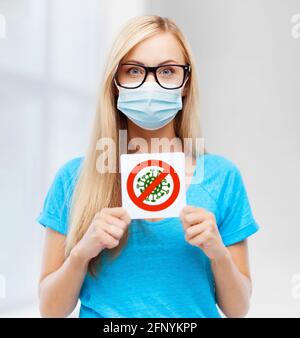 Frau in medizinischer Maske mit Coronavirus-Zeichen Stockfoto