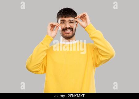 Schwülicher junger Mann in Brille und gelbem Sweatshirt Stockfoto