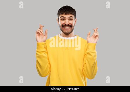 Lächelnder Mann mit gekreuzten Fingern Stockfoto