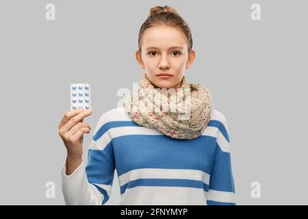 Krankes Teenager-Mädchen im Schal mit Medikamenten-Pillen Stockfoto