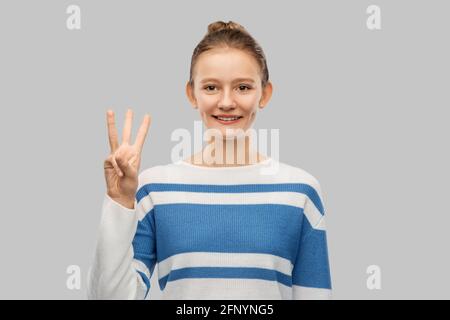 Lächelndes Teenager-Mädchen, das drei Finger zeigt Stockfoto