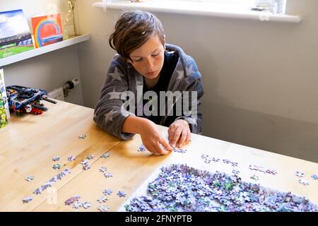 Boy 11 Konzentration auf die Arbeit an Puzzle auf Küchentisch Zu Hause während der Sperrung der Pandemie von Covid 19 im Jahr 2021 in Großbritannien Großbritannien KATHY DEWITT Stockfoto