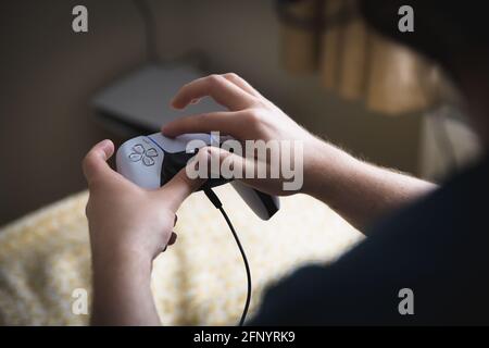 YORK, GROSSBRITANNIEN - 9. MAI 2021. Nahaufnahme eines Jungen im Teenageralter, der einen PS5-Controller hält und den Joypad mit seinen Fingern verwendet Stockfoto