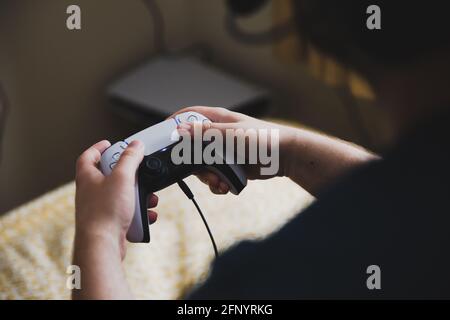 YORK, GROSSBRITANNIEN - 9. MAI 2021. Nahaufnahme eines Jungen im Teenageralter, der einen PS5-Controller in der Hand hält, während er Videospiele spielt Stockfoto