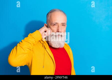 Fotoporträt eines ernsthaften alten Mannes, der Sportkleidung trägt und Schnurrbart berührt Isoliert auf lebhaftem blauen Hintergrund Stockfoto