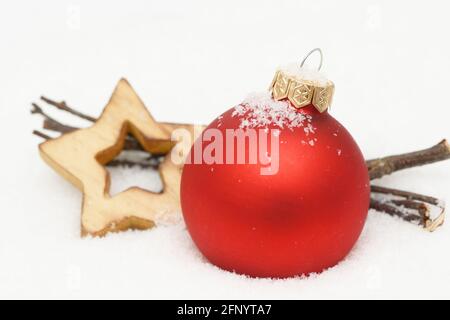 Roter weihnachtsschmuck, Ast und Holzstern liegen im Schnee Stockfoto