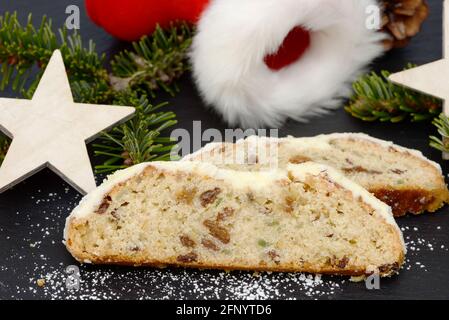 weihnachtsstollen mit Tannenzweig, weihnachtsmannschuh und Sternen, die zur weihnachtszeit auf schwarzem Schiefer liegen Stockfoto