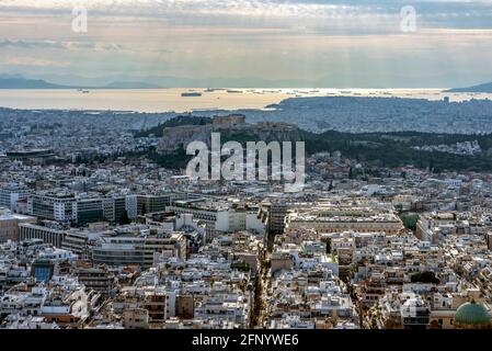 Panoramablick auf das Attika-Becken bei Sonnenuntergang vom Lycabettus-Hügel aus gesehen. Akropolis mit Parthenon-Tempel, Schiffe vor dem Hafen von Piräus, Sonnenstrahlen Stockfoto