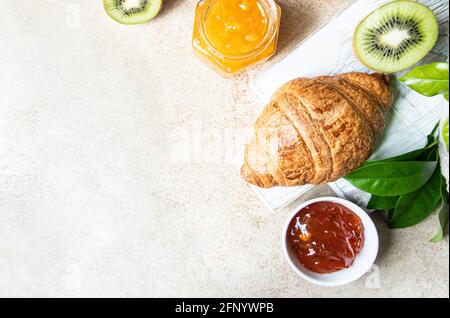 Französisches Croissant mit Marmelade und Kiwi auf hellem Hintergrund. Leckeres Croissant. Speicherplatz kopieren. Draufsicht. Stockfoto