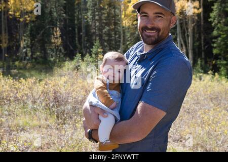 Porträt eines lächelnden Mannes, der seine kleine Tochter im Wald, Kalifornien, USA, hält Stockfoto