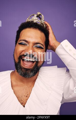 Nahaufnahme eines Mannes, der als Frau gekleidet und lächelnd war. Fröhliche Drag Queen vor lila Hintergrund. Stockfoto
