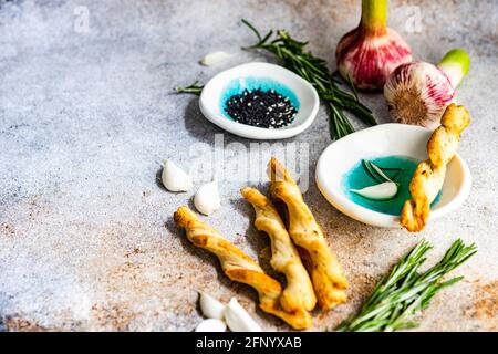 Grissini-Paniermehl mit Olivenöl, Knoblauchzehen, Rosmarin und Sesam Stockfoto