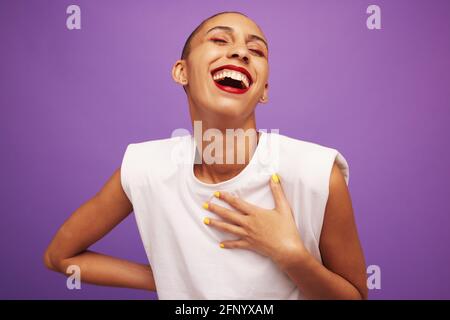 Hübsche Frau in weißem Top lächelt auf Studiohintergrund. Glücklich aussehende Frau mit Make-up auf lila Hintergrund. Stockfoto