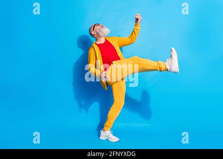 Foto in voller Größe von glücklich aufgeregt verrückt fröhlich Großvater spielen Unsichtbare Gitarre isoliert auf blauem Hintergrund Stockfoto