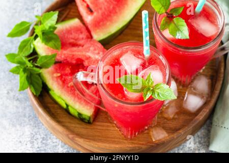 Sommerliches kaltes Getränk. Erfrischendes Wassermelonengetränk in Gläsern und Scheiben Wassermelone auf einer Steinplatte. Stockfoto