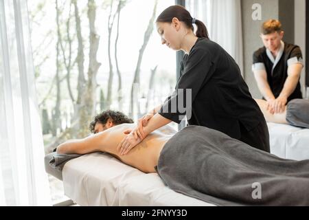 Schönes Paar, das in einem Spa-Salon liegt und genießt eine tiefe Rückenmassage und Entspannung. Wellness und Freizeit für die Gesundheitsfürsorge gemeinsam. Stockfoto