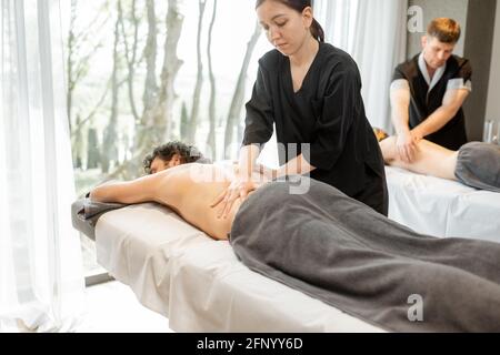 Schönes Paar, das in einem Spa-Salon liegt und genießt eine tiefe Rückenmassage und Entspannung. Wellness und Freizeit für die Gesundheitsfürsorge gemeinsam. Stockfoto