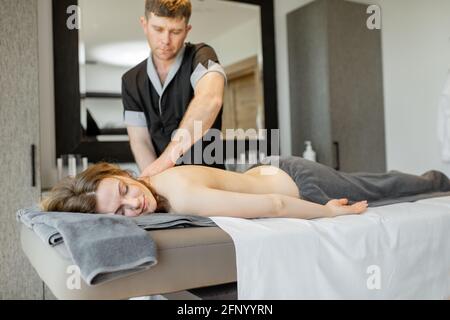 Schöne Frau, die in einem Spa-Salon liegt und genießt eine tiefe Rückenmassage und Entspannung. Wellness und Freizeit für die Gesundheitsfürsorge. Stockfoto