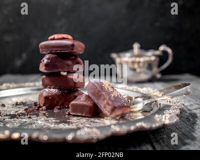Dunkler handgemachter Schokoladenstapel mit Kakaochips und Nüssen Stockfoto