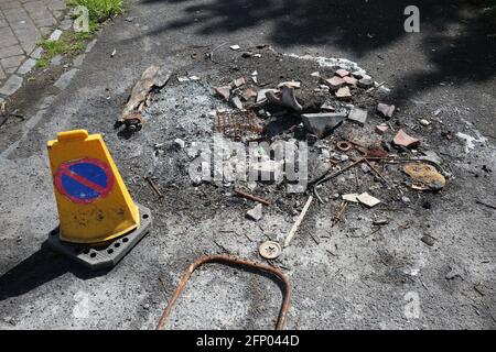 Mülltonne durch Feuer zerstört, das von Vandalen mit Verkehr aufgestellt wurde Kegel warnt Menschen vor der Gefahr Stockfoto