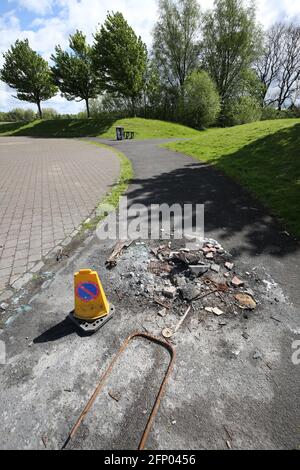 Mülltonne durch Feuer zerstört, das von Vandalen mit Verkehr aufgestellt wurde Kegel warnt Menschen vor der Gefahr Stockfoto