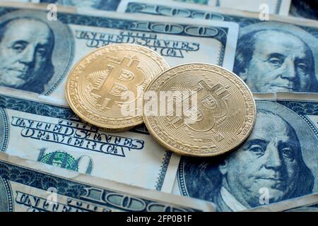 Zwei Goldmünzen aus Bitcoin-Kryptowährung liegen auf hundert Dollarscheine Stockfoto