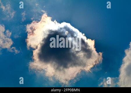 Die Sonne scheint durch eine Wolke in einem blauen Himmel Stockfoto