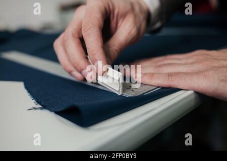 Nahaufnahme der Finger eines Schneiders, der eine Linie über die Details der Kleidung zeichnet. Stockfoto