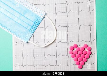 Ein Haufen roter Pillen in Herzform auf dem Kardiogramm. Medizinisches Konzept. Stockfoto