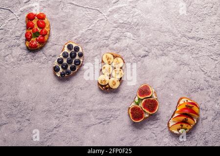 Hausgemachter Sommertoast mit Frischkäse, Nussbutter und Früchten und Beeren, Draufsicht. Stockfoto