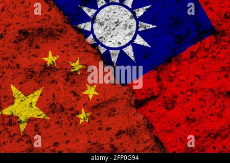 Konzept eines Konflikts zwischen der Volksrepublik China und der Republik China (Taiwan) mit bemalten Fahnen an einer rauen Wand mit einem Riss Stockfoto