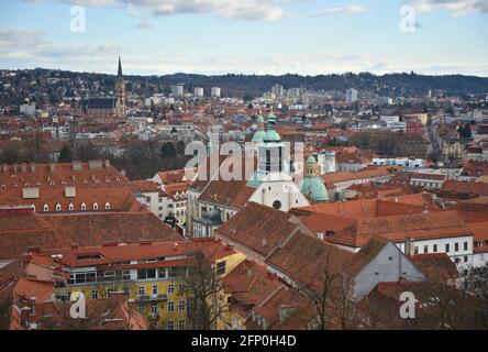 Barocke Gebäude mit roten Ziegeldächern und einem gotischen Glockenturm im Vordergrund in Graz, der Hauptstadt der Steiermark in Österreich. Stockfoto