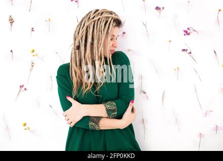 Fröhliche junge Frau in bunten Outfit Blick auf die Kamera mit Lächeln und schütteln Dreadlocks isoliert auf weißem Hintergrund Stockfoto