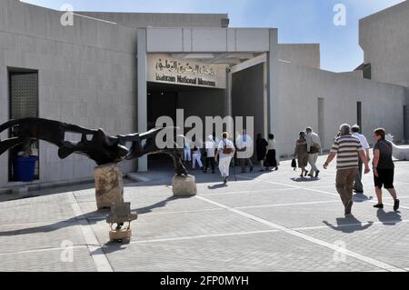 Eine Gruppe von Kreuzfahrt-Passagieren kommt im Sightseeing-Reisebus an Führung durch das Bahrain National Museum unter dem zweisprachigen Schild, Eingang in Manama Stockfoto