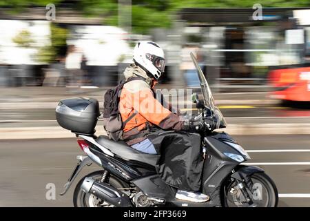 Belgrad, Serbien - 13. Mai 2021: Ein Mann, der an einem sonnigen Tag nach dem Regen auf der Stadtstraße auf einem Roller reitet Stockfoto