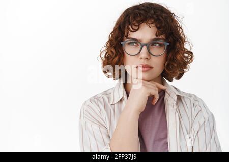 Serious nachdenkliches Mädchen in der Brille, Student denken, Blick links auf Werbung und Nachdenken, Entscheidung treffen, einen Gedanken haben, stehen über Stockfoto