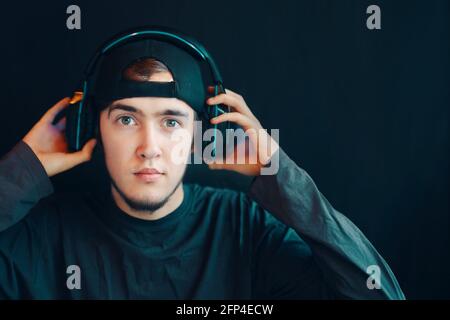 Cyber-Sport. Young Handsome Spiel Streamer gewinnt schließlich eine Runde in einem wettbewerbsorientierten Spiel. Kerl in der Mütze zieht seine Kopfhörer aus. Stockfoto