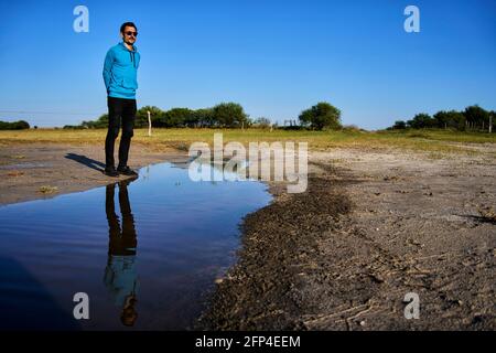 Lächelnder junger Mann spiegelte sich im Wasser wider Stockfoto