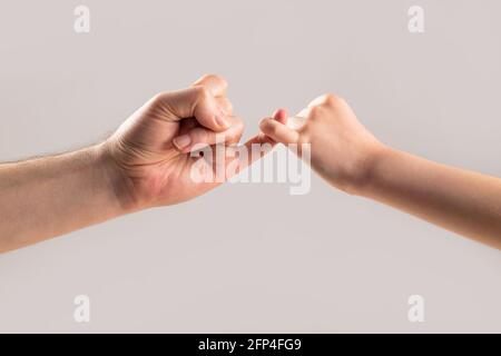 Der kleine Finger der beiden Hände hält sich zusammen. Zeige Freundschaft und Vergebung. Freundschaft von Generationen. Vater, Tochter Hand macht Versprechen Stockfoto