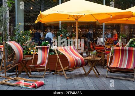 London, Großbritannien, 20. Mai 2021: Windiges Wetter lässt Liegestühle im Restaurant der Raffinerie nahe der South Bank stürmeln. Aber aufgrund der jüngsten Lockerung der Coronavirus-Vorschriften sind die Gäste jetzt glücklich drinnen, vorausgesetzt, sie folgen der Regel der sechs. Anna Watson/Alamy Live News Stockfoto
