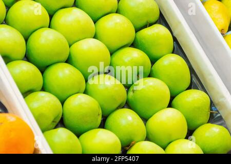 Frische, leuchtend grüne Äpfel sind ordentlich in einer Reihe angeordnet In einer Kiste auf dem Markt in der Supermarkttheke Stockfoto